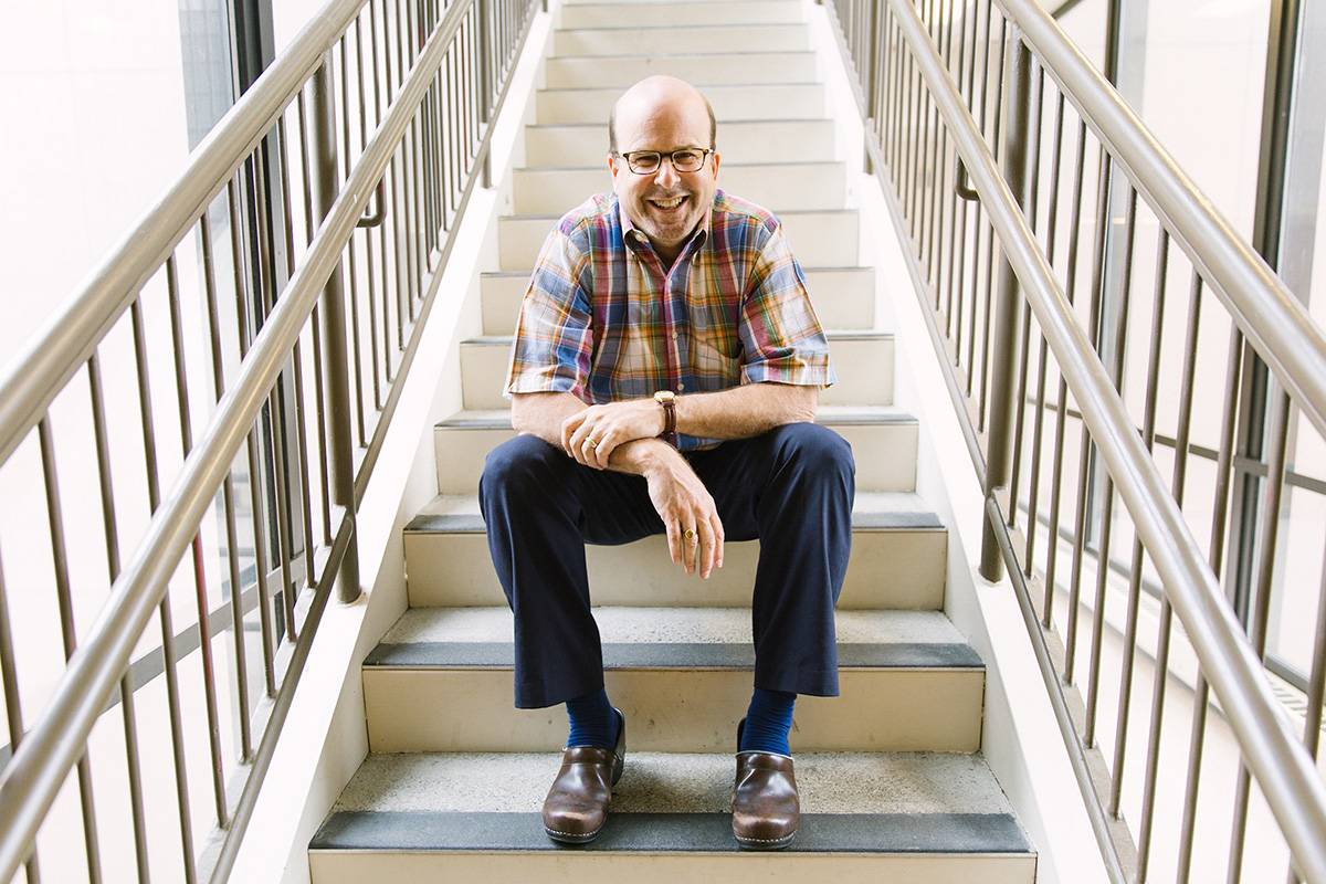 Ken Steinberg smiling, seated on a stairway.