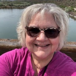 Keli Lock wearing sunglasses, looking into the camera and smiling. 